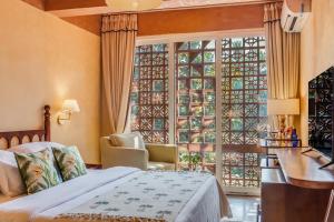a bedroom with a bed and a large window at Unseen Boutique Hotel, Assagao in Assagao +50 photos