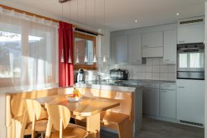 a kitchen with a wooden table with chairs and a tableasteryasteryasteryasteryastery at Chalet Capricorn in Bettmeralp +3 photos