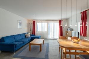a living room with a blue couch and a table at Chalet Capricorn in Bettmeralp