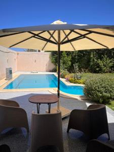 a table with an umbrella next to a swimming pool at King mariout villa LA FIESTA in Borg El Arab