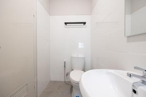 a white bathroom with a toilet and a sink at Sans Stay Bintaro in Pondoklang