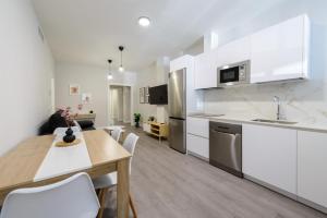 a kitchen with white cabinets and a table and chairs at Torrejón Suites in Torrejón de Ardoz +50 photos