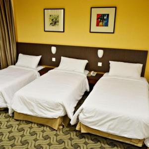 two beds in a hotel room with white sheets at YMCA Kuala Lumpur in Kuala Lumpur