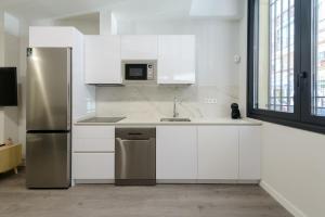 a kitchen with white cabinets and a stainless steel refrigerator at Torrejón Suites in Torrejón de Ardoz