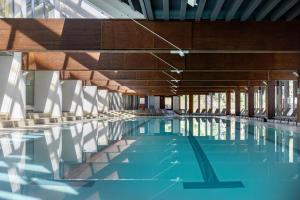 a swimming pool with blue water and wooden ceilings at Blu Senales Active & Family Resort in Maso Corto +40 photos