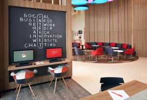 a waiting room with tables and chairs and a chalkboard at Ibis Saigon Airport in Ho Chi Minh City