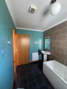 a bathroom with a bath tub and a sink at Crofters Cottage Barra  +23 photos