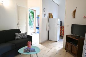 a living room with a couch and a table and a refrigerator at Ti' Palmiers in Pointe-Noire