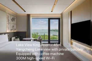 a hotel room with a large window with a tv at Suzhou Marriott Hotel Yangcheng Lake in Suzhou
