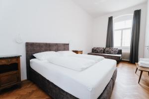 a bedroom with a large white bed and a chair at Rilke Apartments in Linz