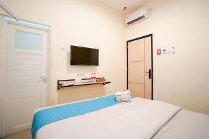 a bedroom with a bed and a tv and a door at Sans Hotel Beskalan Malioboro in Yogyakarta
