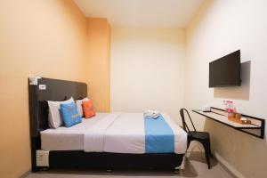 a bedroom with a bed and a desk and a television at Sans Hotel Beskalan Malioboro in Yogyakarta