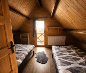 a attic room with two beds and a window at Chata Nikki in Vrbno pod Pradědem
