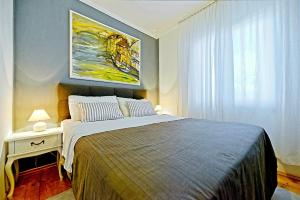 a bedroom with a bed and a painting on the wall at Apartments with parking space Postira, Brac - 2913 in Postira