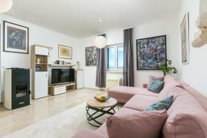 a living room with a pink couch and a tv at Apartments with parking space Postira, Brac - 2913 in Postira