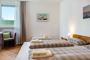 a bedroom with two beds and a chair and a window at Ferienwohnung Alex in Meersburg