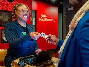 a woman giving a man a credit card and a laptop at Ibis Styles Paris Gare de l'Est Magenta in Paris