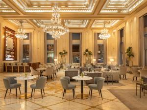 a dining room with tables and chairs and chandeliers at The Plaza, A Fairmont Hotel in New York