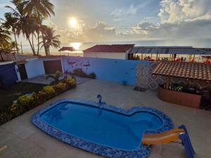 a swimming pool on a patio with the ocean in the background at Casa beira mar com piscina Coruripe Povoado Miai de cima in Coruripe