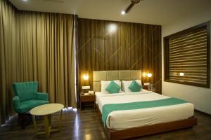 a hotel room with a bed and a chair at Hotel Krinoscco in Ayodhya +12 photos