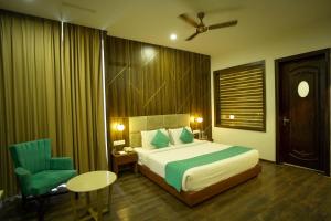 a bedroom with a bed and a chair and a table at Hotel Krinoscco in Ayodhya