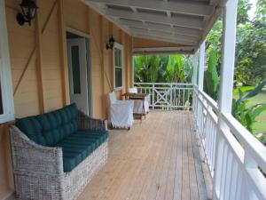 una veranda con divano e tavolo su una casa di Whitsunday Cane Cutters Cottage a Cannon Valley