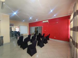 a conference room with black chairs and a red wall at Mimos Hotel in Tete
