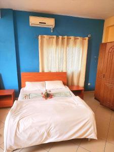a bedroom with a large white bed with a blue wall at Mimos Hotel in Tete