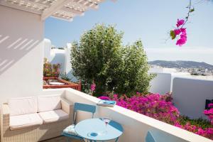 a balcony with a table and chairs and purple flowers at Ibiscus down town location Myconos in Megali Ammos