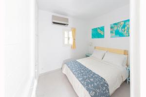 a white bedroom with a bed and a window at Ibiscus down town location Myconos in Megali Ammos