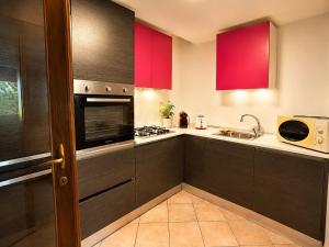 a kitchen with red cabinets and a stove top oven at Villa Pineta Grande in Lignano Sabbiadoro