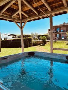 a hot tub in a backyard with a wooden roof at Podere Cerretini in Montepulciano
