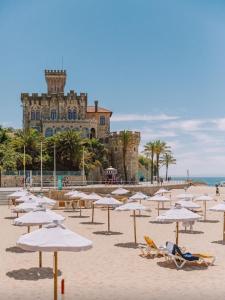 a beach with chairs and umbrellas in front of a building at Casa Rosa in Parede