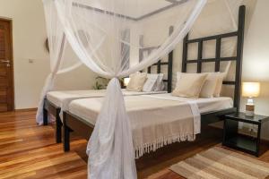a bedroom with two beds with white drapes at Jambiani Villas in Jambiani