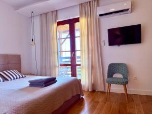 a bedroom with a bed and a chair and a television at Apartmán Zara in Komárno +23 photos