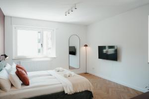 a white bedroom with a large bed and a mirror at The Haus HANS Nuremberg in Nuremberg