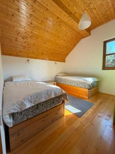 two beds in a room with a wooden ceiling at VIG 2 in Njegovuđa