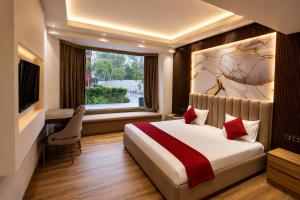 a bedroom with a bed and a desk and a window at The Aura Hotel & Resort in Noida