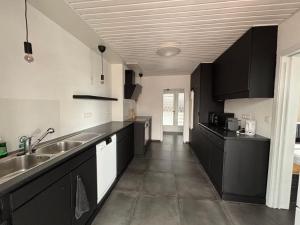 a kitchen with black cabinets and a sink at Le Gîte du Trieux - Berzée in Berzée