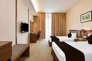 ein Hotelzimmer mit zwei Betten und einem Fernseher in der Unterkunft Sunday Near Gerbang Malam Ipoh Formerly Seemsoon in Ipoh
