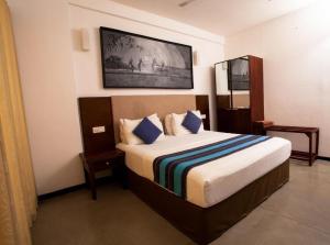 a bedroom with a large bed with blue pillows at Grand Hotel Villa Ella in Bandarawela