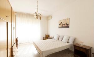a white bedroom with a bed and a window at la casa rossa in Suni