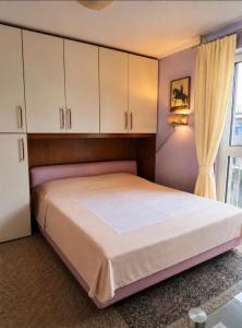 a bedroom with a bed with white cabinets and a window at Home for 2 few steps from center of Monte Carlo in Beausoleil