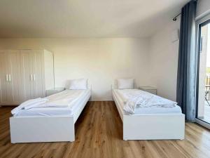 two beds in a room with wooden floors at AM102 moderne Monteurwohnung in Amberg +1 photo