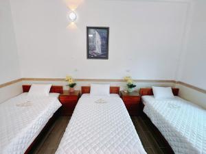 a room with three beds and a picture on the wall at Bảo Yến HOTEL in Bản Khe Rạn +2 photos