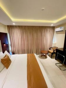 a hotel room with a large bed and a chair at Lagos Airport Hotel in Ikeja