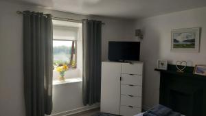 a bedroom with a television and a dresser with a window at The Smithy at 52 Vatisker in Stornoway