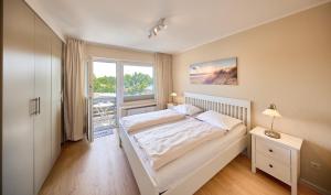 a bedroom with a large white bed and a window at Haus Schildt, FeWo 1 in Duhnen