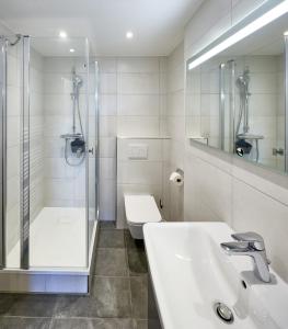 a bathroom with a shower and a sink and a toilet at Haus Schildt, FeWo 1 in Duhnen