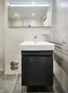 a bathroom with a white sink and a mirror at Haus Schildt, FeWo 1 in Duhnen +15 photos